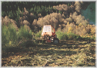 Desbrozadora de cadenas, accionada por tractor agr&iacute;cola de cadenas, que avanza marcha atr&aacute;s